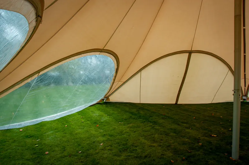 Binnenzicht van een stertent met een doorzichtige panorama-zijwand en een gesloten ecru zijwand